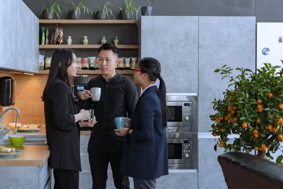 Een moderne kantoor pantry met koelapparatuur, koffiezetapparaat en snacks, die bijdraagt aan een efficiënte werkomgeving.