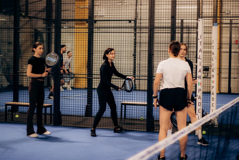 Een speler die een padelracket vasthoudt op de baan, klaar voor actie met een focus op kracht en controle.
